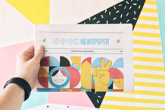 a hand holding a design newspaper